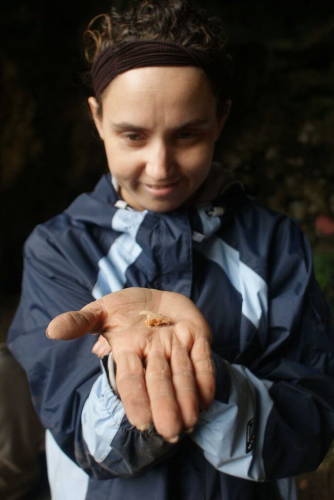 Amanda Finleyy holding a rat skull at a site in Fiji that dates back about 750 years. She has her hand extended with the tiny skull on it, and is wearing a gray jacket